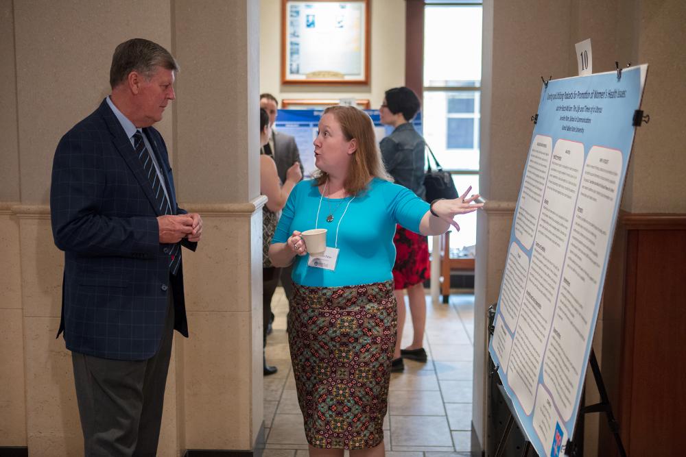 Student is presenting a poster to President T. Haas